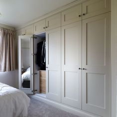 a bedroom with white closets and carpeted flooring