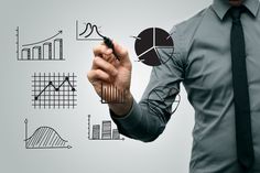 a man in a tie writing on a whiteboard with graphs and pies drawn on it