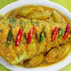 a white plate topped with meat covered in sauce and peppers on top of green cloth