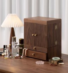 a wooden cabinet sitting on top of a table next to a lamp and other items