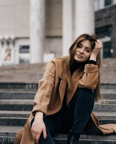 a woman is sitting on the steps in front of a building with her hand on her head