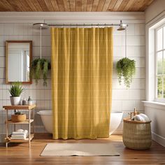 a yellow shower curtain in a bathroom with wood floors and white tile walls, potted plants on the window sill