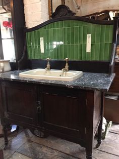 an old fashioned sink with green tiles on the wall