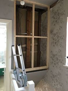 an unfinished room is shown with the window being installed and wallpapered behind it