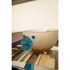 a glass bowl sitting on top of a table next to a book shelf with books