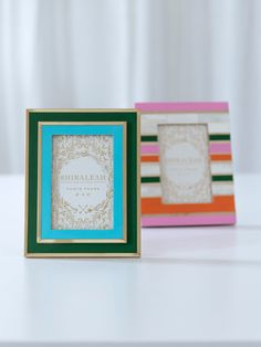 two different colored frames sitting next to each other on a white counter top, one with a blue and green border