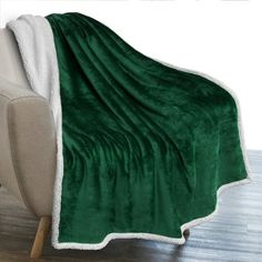 a green and white blanket sitting on top of a couch next to a wooden floor