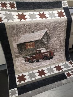 an old truck is parked in front of a barn with stars on the quilts