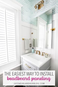 a bathroom with blue and white wallpaper, gold faucet, and large mirror