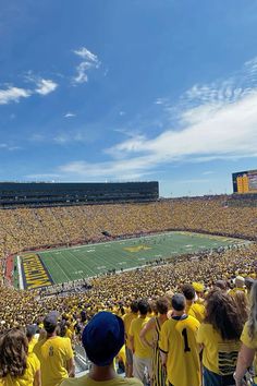 a football stadium full of people watching the game on a sunny day with blue skies