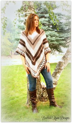 a woman standing in front of a tree wearing boots and a ponchy shawl