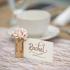 a place card holder with a rose on it next to a cup and saucer