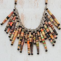 a multicolored necklace is hanging from a chain on a white wooden surface with other beads