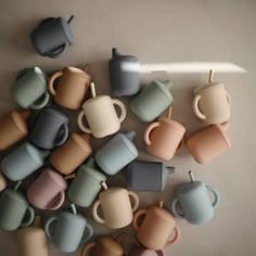 there are many different cups and mugs on the table together, all in pastel colors