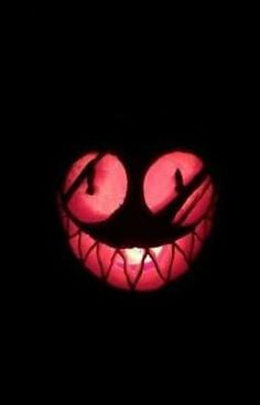 a close up of a face in the dark with glowing eyes and fangs on it