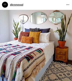 a bed sitting in a bedroom next to two planters and mirrors on the wall