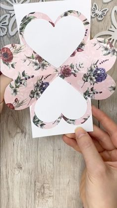 someone holding up a paper cutout with flowers and hearts in the shape of a cross