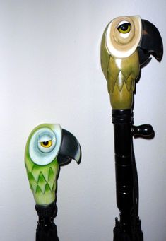 two colorful umbrellas with black handles and green feathers, one has an owl's head on it