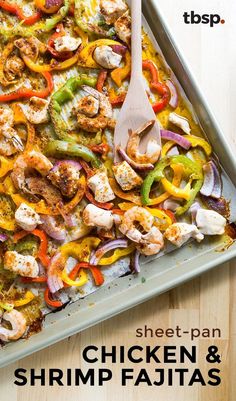 a sheet pan filled with chicken and shrimp fajitas on top of a wooden table