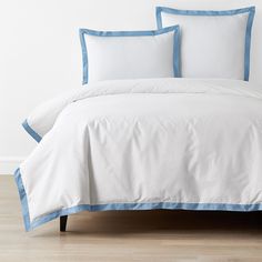 a white bed with blue trim and pillows