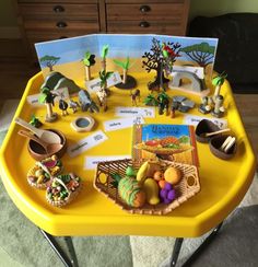 a yellow tray filled with different types of toys on top of a carpeted floor