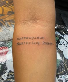 a person with a tattoo on their arm that says masterpiece, mastering peace in black ink