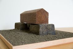 a wooden block sitting on top of a pile of dirt next to a building with a roof