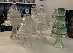 four glass candlesticks sitting on top of a white counter next to a shelf