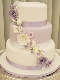 a three tiered wedding cake with purple and white flowers