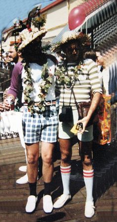 two men standing next to each other in shorts and socks with flowers on their chests