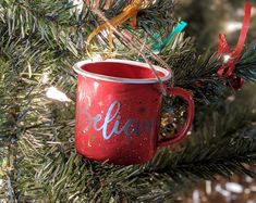 a red coffee mug hanging from a christmas tree