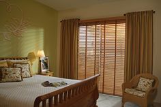 a bed sitting in a bedroom next to a window with wooden blinds on top of it