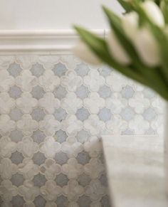 a vase filled with white flowers sitting on top of a counter next to a wall