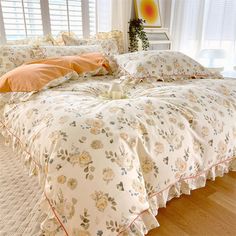 a bed with yellow flowers on it in a bedroom next to a window and white curtains