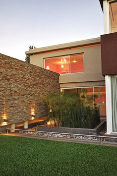 an exterior view of a modern house with grass in the foreground and lights on