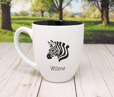 a white coffee mug with a zebra head on the side and willow in the background