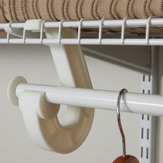 an apple hanging from the side of a white shelf next to a metal rack with hooks