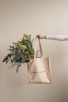 a person holding a bag with flowers in it and the words smell space printed on it