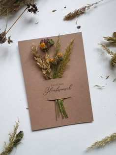 some dried flowers are laying on top of a piece of brown paper that says congratulations