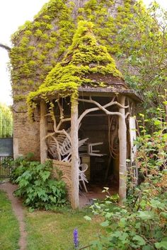 an old building with vines growing on it's roof and door, surrounded by greenery