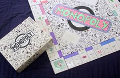 two monopoly board games are laying on a blue cloth covered tablecloth, one has an unopened box and the other has a sticker that says monopoly