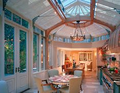 a kitchen and dining area with glass roofing on the ceiling, windows to the outside