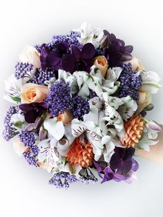 a bouquet of purple and orange flowers on a white surface