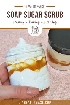 a hand holding a jar filled with homemade soap scrubs on top of a pink towel