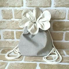 a black and white striped bag with a flower on the front, sitting against a brick wall