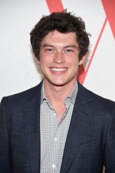 a young man in a suit smiling at the camera