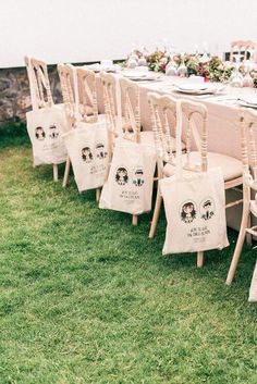 a long table set up with chairs and place settings for an outdoor wedding reception in the grass