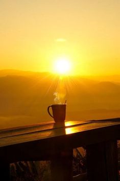 a coffee cup sitting on top of a wooden table next to the sun in the sky