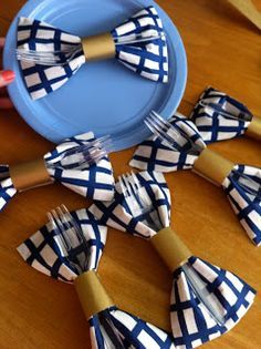 a table topped with blue and white plates covered in paper bow tie napkins on top of a wooden table