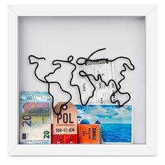 a white frame with a world map and some different items in it that are hanging on the wall